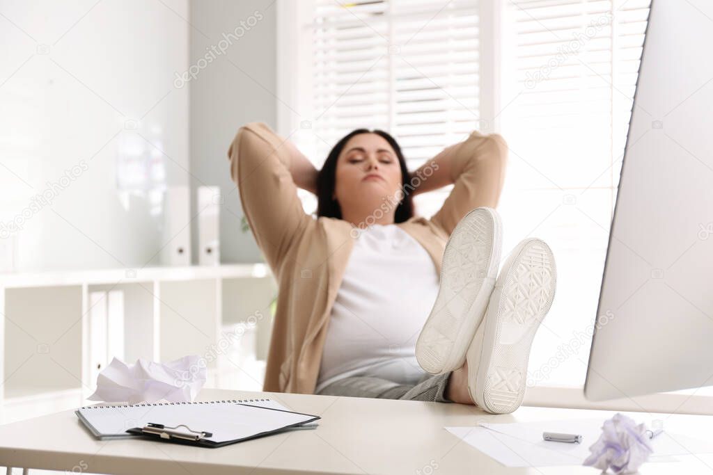 Lazy overweight worker with feet on desk in office