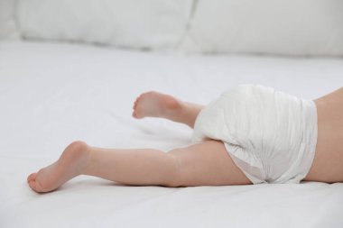 Yatakta bebek bezi içinde şirin bir bebek, yakın plan.