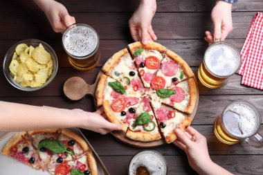 Lezzetli pizzalı arkadaşlar Diablo ve ahşap masada bira, üst manzara.