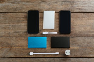 Düz kompozisyon, cep telefonları ve portatif şarjlı tahta arka plan.