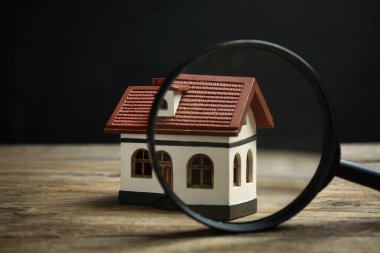 Ev modeli ve ahşap masada büyüteç. Arama konsepti