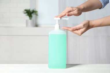 Kapalı mekanda antiseptik jel kullanan bir kadın.