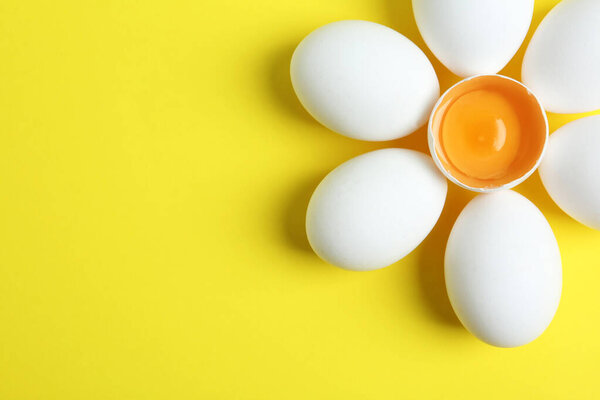 Fresh raw chicken eggs on yellow background, flat lay. Space for text