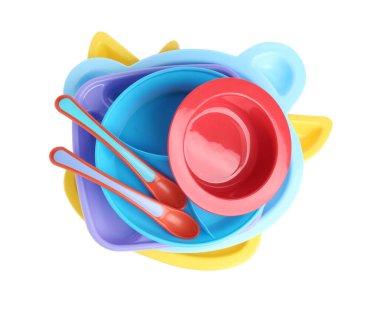Renkli plastik bulaşık takımı yığını beyaza izole edilmiş, en üstte bebek maması servis ediliyor.