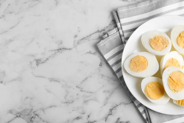 Tasty hard boiled eggs on white marble table, flat lay. Space for text