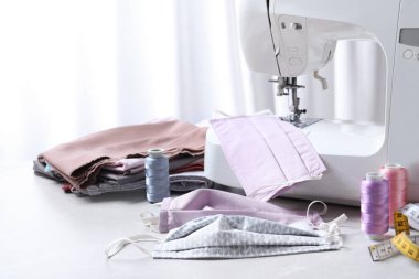 Dikiş makinesi, ev yapımı koruyucu maskeler ve masadaki el işi aksesuarlar.