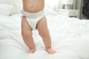 Yatakta bebek bezi içinde şirin bir bebek, yakın plan. Metin için boşluk