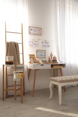Beyaz duvarın yanında yaratıcı işyeri olan şık bir oda.