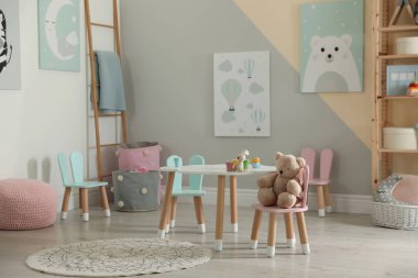 Küçük masa ve çocuk odasının içinde tavşan kulaklı sandalyeler.