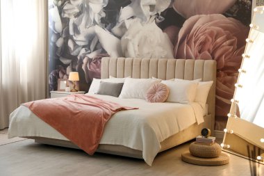 Büyük yataklı, aynalı ve çiçek desenli güzel bir oda.