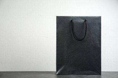 Masadaki siyah alışveriş poşeti, arka plandaki ışığa karşı. Metin için boşluk