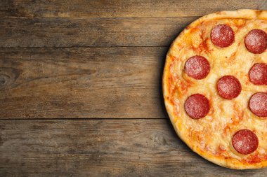 Ahşap masada nefis pepperonili pizza, üst manzara. Metin için boşluk