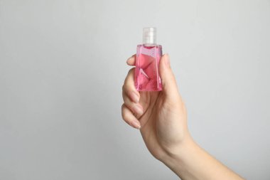 Açık gri arka planda antiseptik jel tutan kadın, yakın plan.