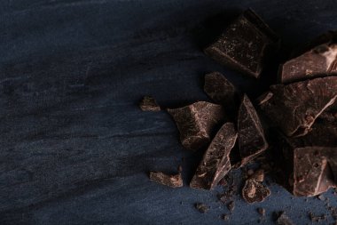 Mavi mermer masanın üzerinde, düz bir şekilde duran koyu çikolata parçaları. Metin için boşluk