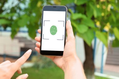 Dışarıda parmak izi sensörü olan akıllı telefonu tutan kadın, yakın plan. Dijital kimlik