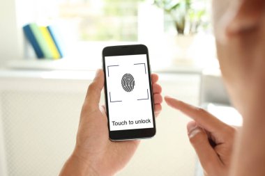 Kapalı alanda parmak izi sensörü olan akıllı telefonu tutan adam, yakın plan. Dijital kimlik