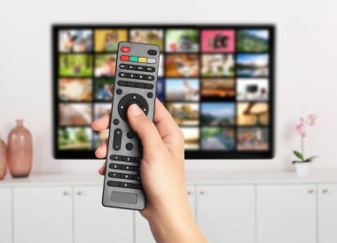 Yayınlanan video servisleri. TV 'de kanal değiştirmek için uzaktan kumanda kullanan kadın, kapat