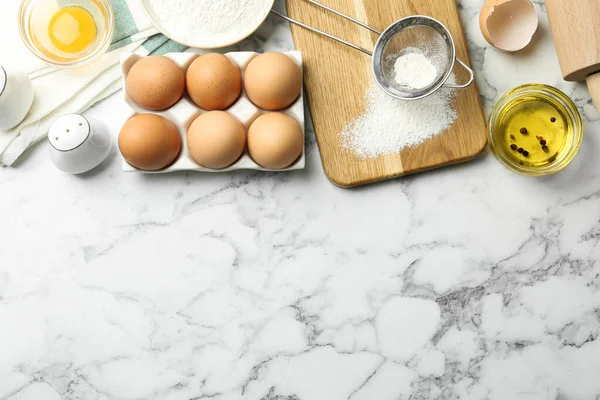 Flat lay composition with chicken eggs on white marble table. Space for text