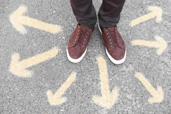 Man standing on road near arrows, closeup