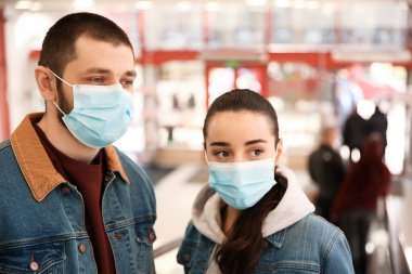 Alışveriş merkezinde tek kullanımlık maskeler takan bir çift. Tehlikeli bir virüs.