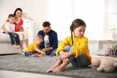 Ebeveynler diğer çocuklarla evde vakit geçirirken mutsuz küçük kız kıskançlık hissediyor.