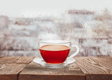 Yağmurlu bir günde pencerenin yanında bir bardak sıcak çay 