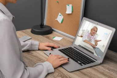 Yetişkin kadın doktorla çevrimiçi istişare için dizüstü bilgisayar kullanan bir kadın. 