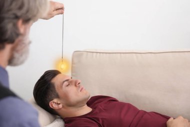 Ofiste hipnoterapi seansı sırasında sarkacı kullanan psikoterapist.