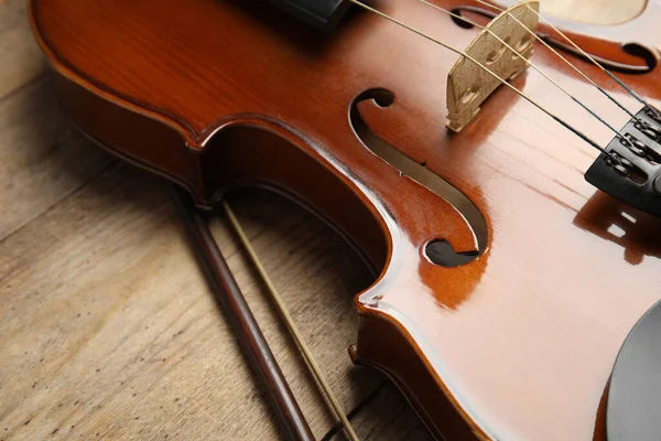 Beautiful violin and bow on wooden table, closeup