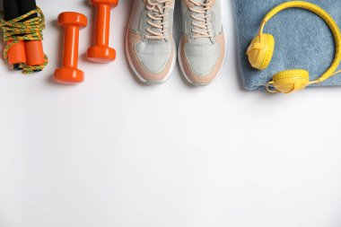 Düz kompozisyon, fitness ekipmanları ve kulaklıklar beyaz arka planda. Metin için boşluk