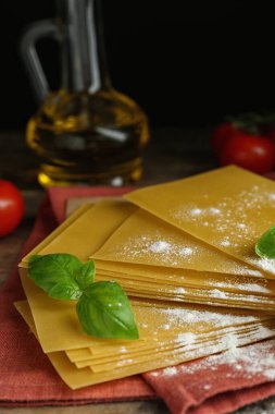 Ahşap masanın üzerinde pişmemiş lazanya çarşafları olan kompozisyon