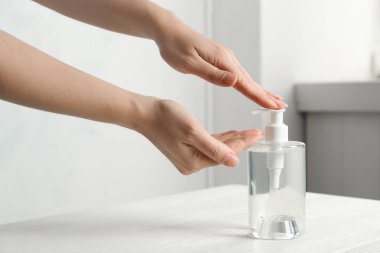 Kapalı mekanda antiseptik jel kullanan bir kadın.