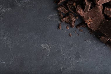 Gri masadaki lezzetli siyah çikolata parçaları, üst manzara. Metin için boşluk