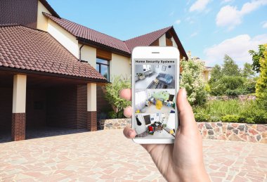 Alarm sistemi. Evinin yakınındaki akıllı telefondan modern kameraları izleyen bir kadın.