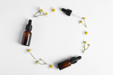 Beyaz arka planda gerekli yağ şişeleri ve papatya çaylarıyla yapılmış bir çerçeve. Metin için boşluk