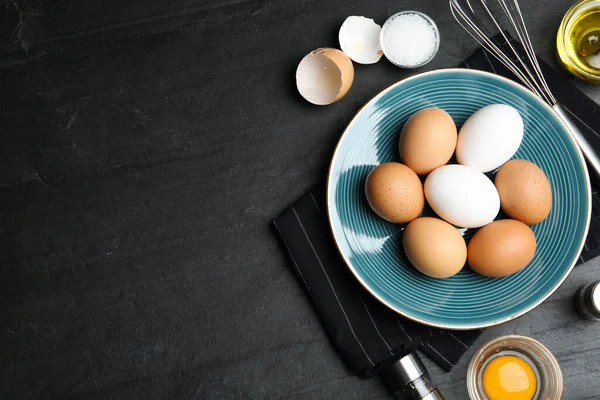 Flat lay composition with chicken eggs on black table. Space for text