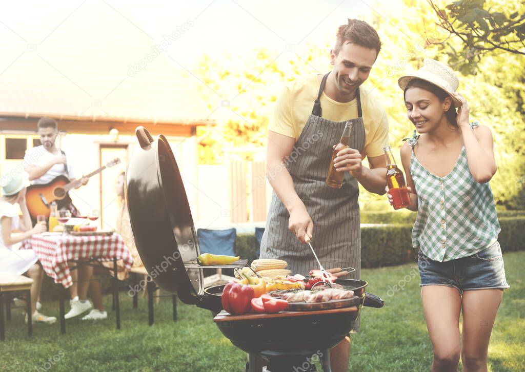 Young man and woman near barbecue grill outdoors on sunny day