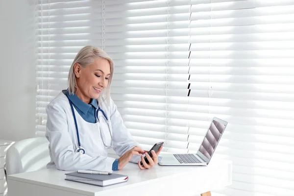 Médico Femenino Maduro Con Teléfono Inteligente Mesa Oficina — Foto de Stock