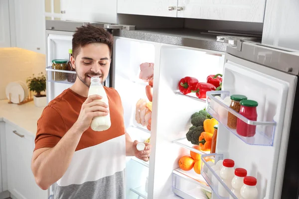 Mladý Muž Pije Mléko Blízkosti Otevřené Ledničky Kuchyni — Stock fotografie