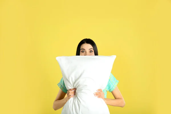 黄色の背景に枕を持つ若い女性 — ストック写真