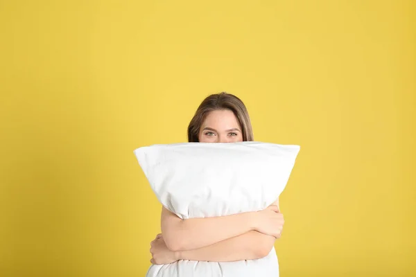黄色の背景に枕を持つ若い女性 — ストック写真