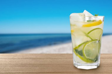 Plajdaki ahşap masada buz küplü limonata, metin için yer.