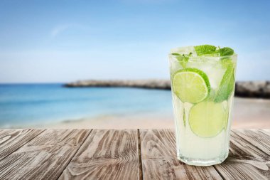Buz küplü lezzetli limonata ve deniz kenarındaki ahşap masada limonata.