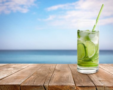 Buz küplü lezzetli limonata ve deniz kenarındaki ahşap masada limonata.