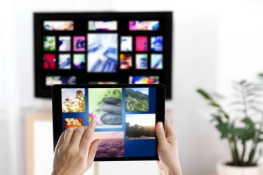 Yayınlanan video servisleri. TV 'de kanal değiştirmek için tablet kullanan kadın, kapat