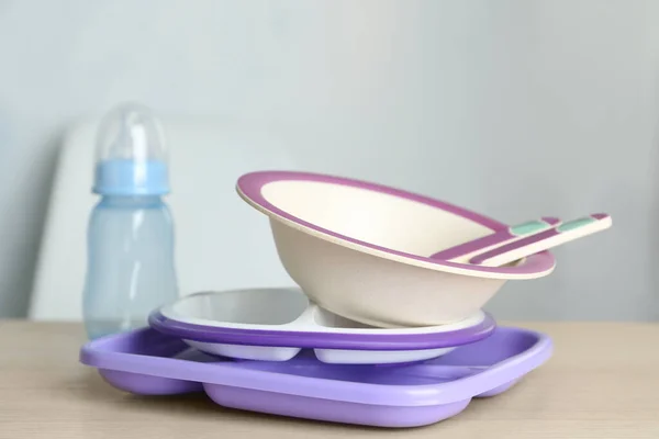 Set of plastic dishware on wooden table indoors. Serving baby food