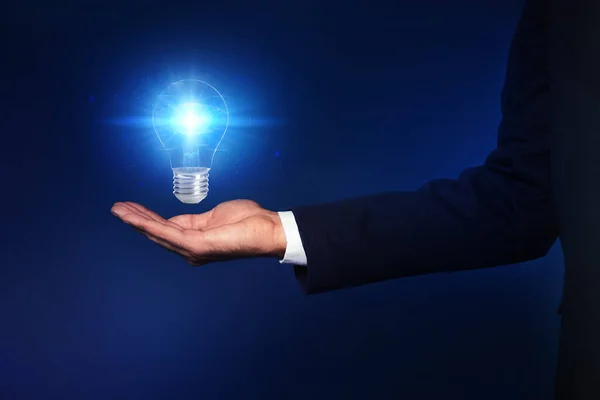アイデアのコンセプト 暗い背景に光る電球を持つビジネスマン クローズアップ — ストック写真