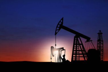 Gün batımında ham petrol pompalarının siluetleri. Metin için boşluk