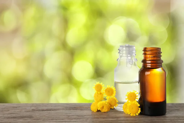 Flaskor Med Eterisk Olja Och Blommor Träbord Mot Suddig Bakgrund — Stockfoto