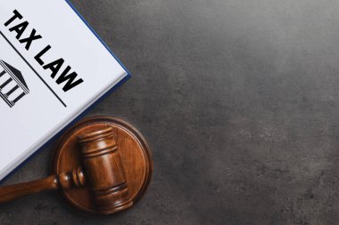 Vergi hukuku kitabı ve gri arka planda tokmak, düz. Metin için boşluk